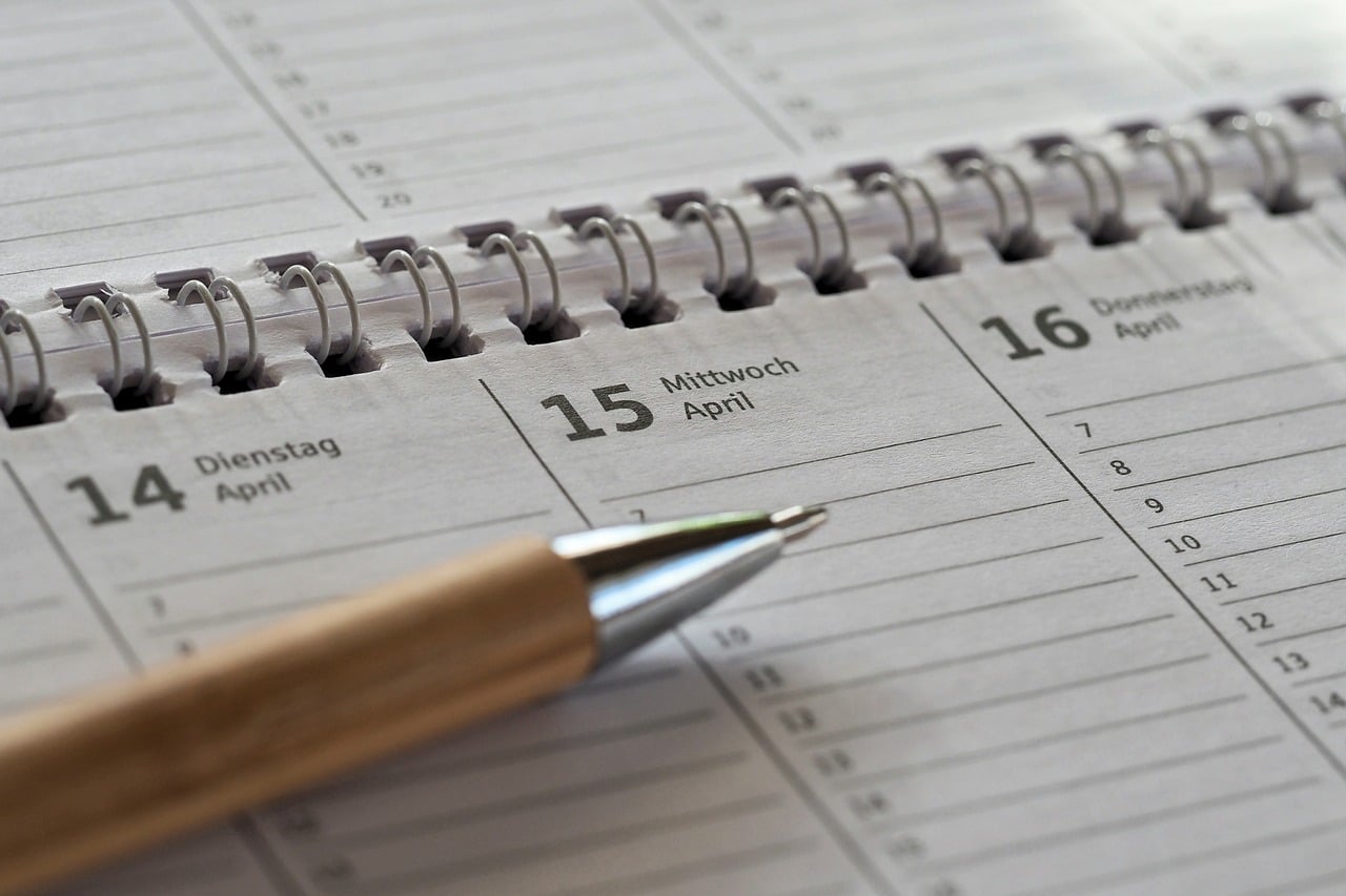 Ein spiralgebundener Papierplaner, aufgeschlagen Mitte April, mit einem quer über der Seite liegenden Stift. Release-Taktung läuft darauf hinaus, wie oft sich diese Daten füllen.