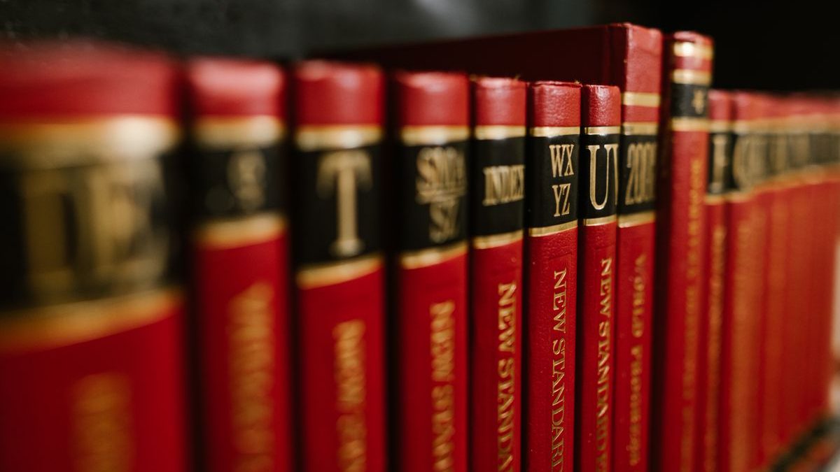 A row of red leather-bound encyclopedia volumes with black labels and gold lettering (T, INDEX, WX YZ, UV) on a shelf, in shallow focus. Most of the logic inside the templates of a large wiki is written with the functions described here.