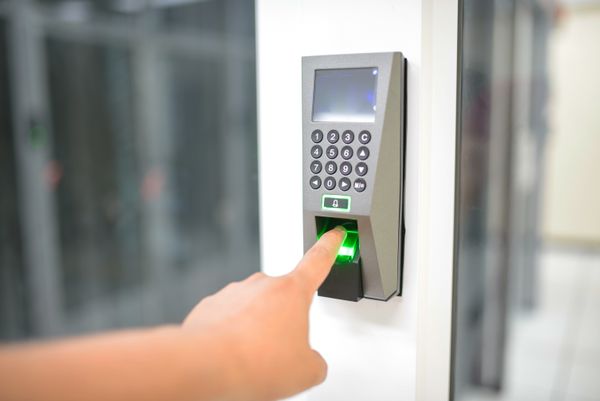 Un doigt sur un scanner de controle d'acces mural a empreinte digitale et clavier