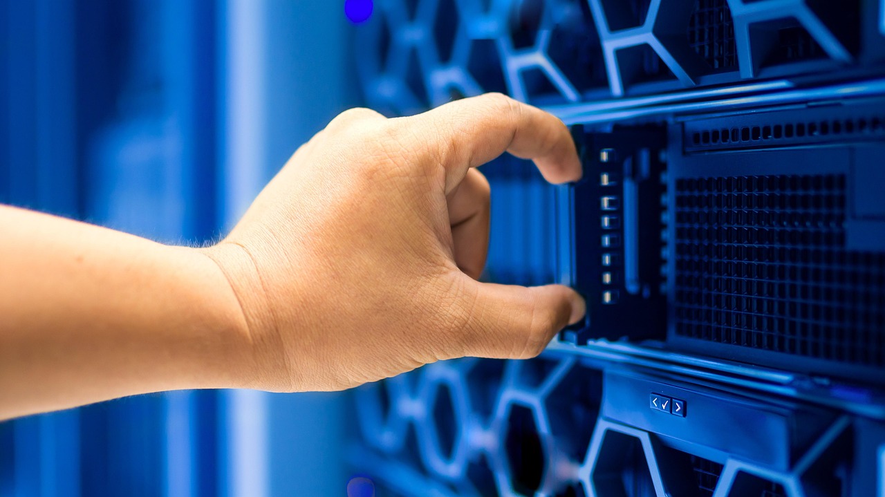 Une main insérant un module serveur dans un rack de data center éclairé en bleu