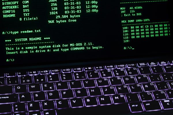 A green-text MS-DOS style terminal screen above a backlit keyboard