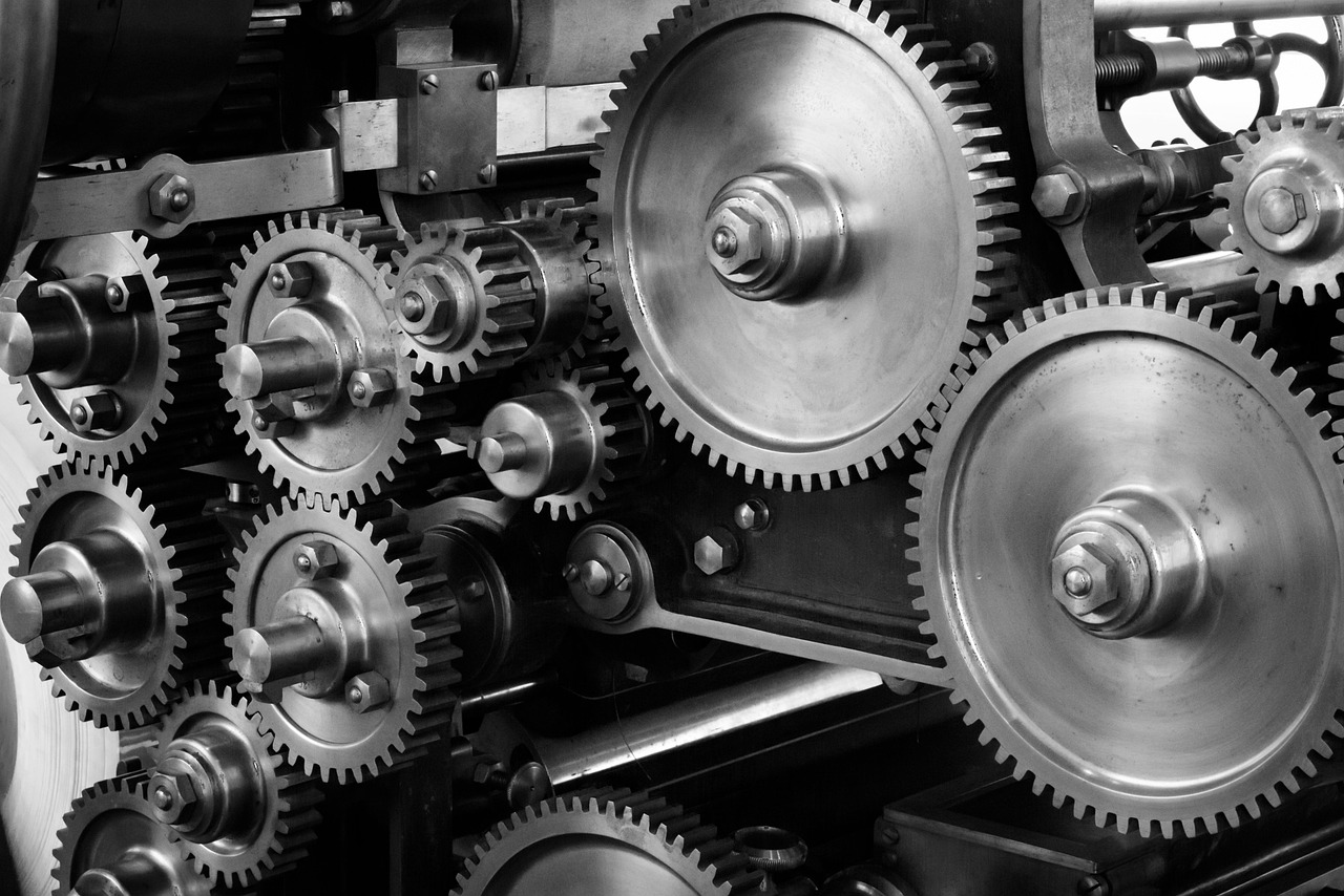 Ingranaggi metallici incastrati dentro una vecchia macchina, fotografati in bianco e nero. Una linea LTS in manutenzione è meccanica tenuta in rotazione: le correzioni entrano, il nuovo no.