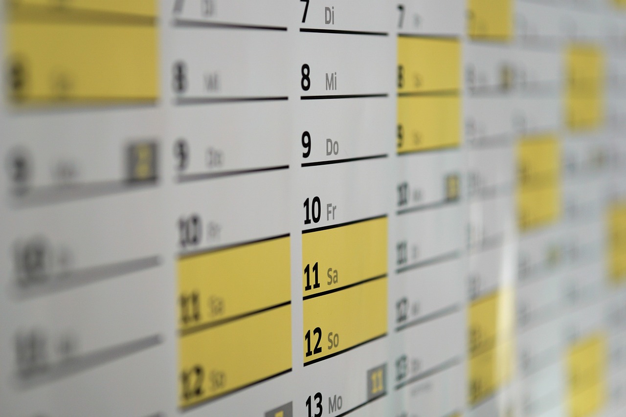 Un calendario da parete ripreso di sbieco, con diverse righe di date evidenziate in giallo