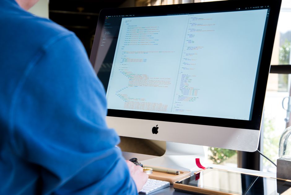 Un desarrollador trabajando en un ordenador de sobremesa, editando código fuente del tipo que Git registra.