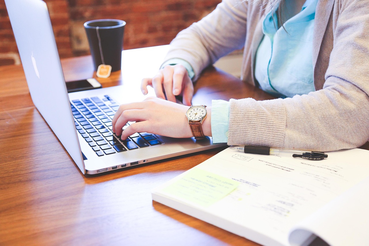 A person typing on a laptop at a desk.